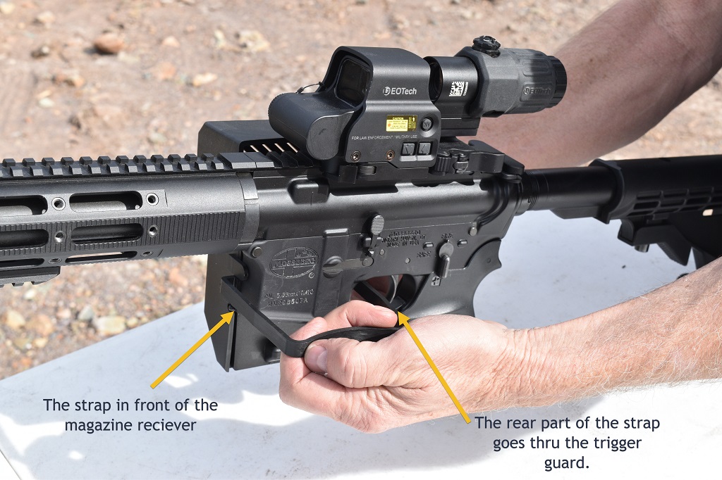 The strap of casing catcher goes in front of the magazine receiver. 